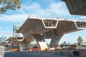 Partially constructed concrete bridge with scaffolding, safety barriers, and construction materials visible; a testament to the infrastructure projects that drive industries forward under a clear sky.